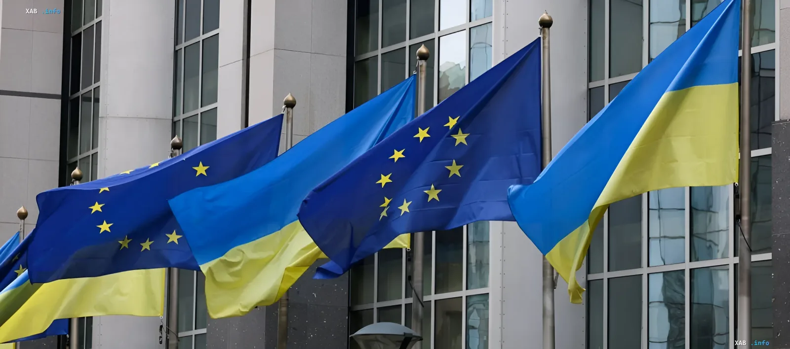 Flags of Ukraine and the European Union waving in front of an EU building, symbolizing the receipt of the seventh financial aid tranche of €2.6 billion for early reforms