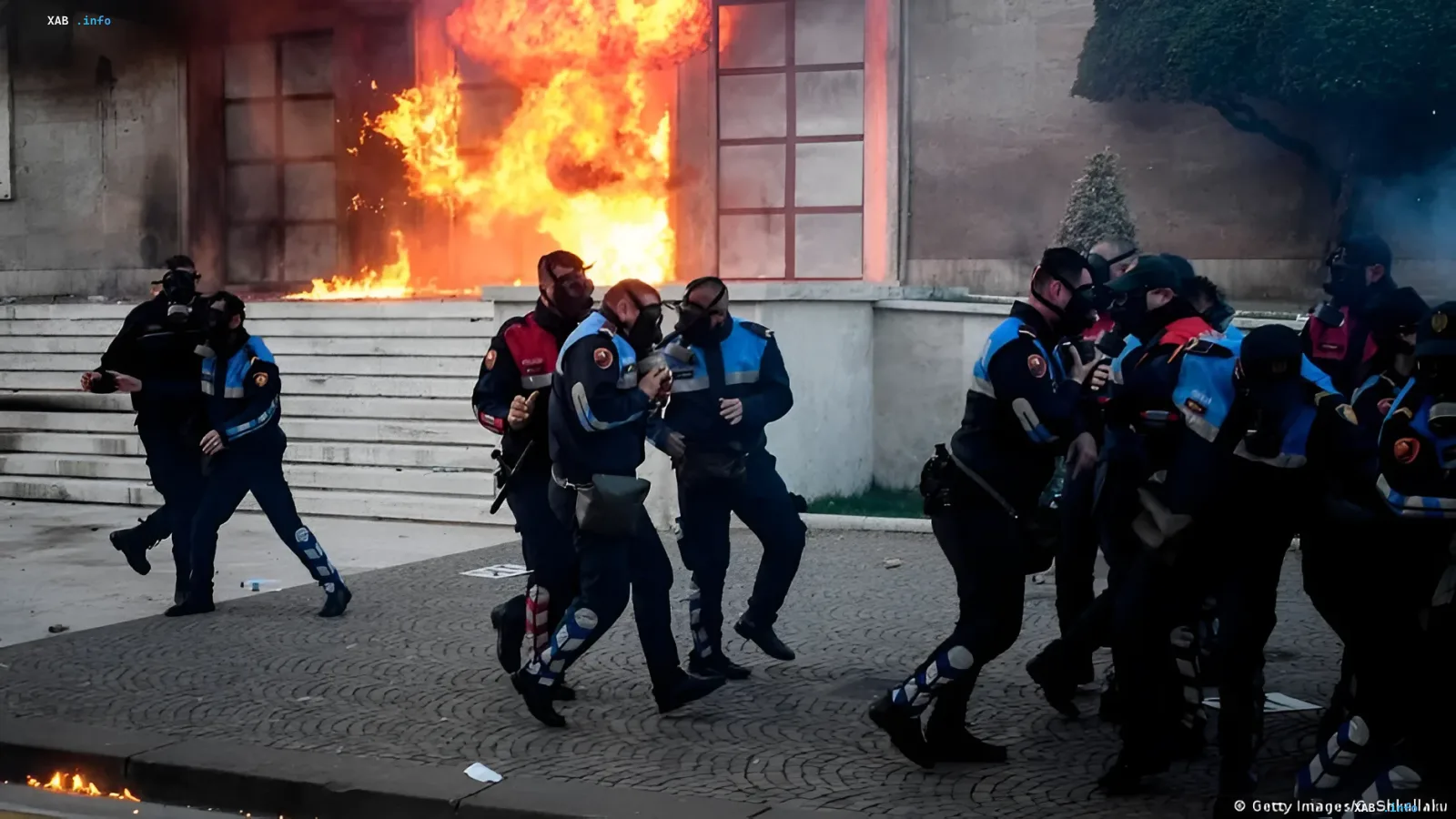 Полицейские в защитных масках бегут от огня во время протестов в Тиране, связанных с проектом курорта Кушнера