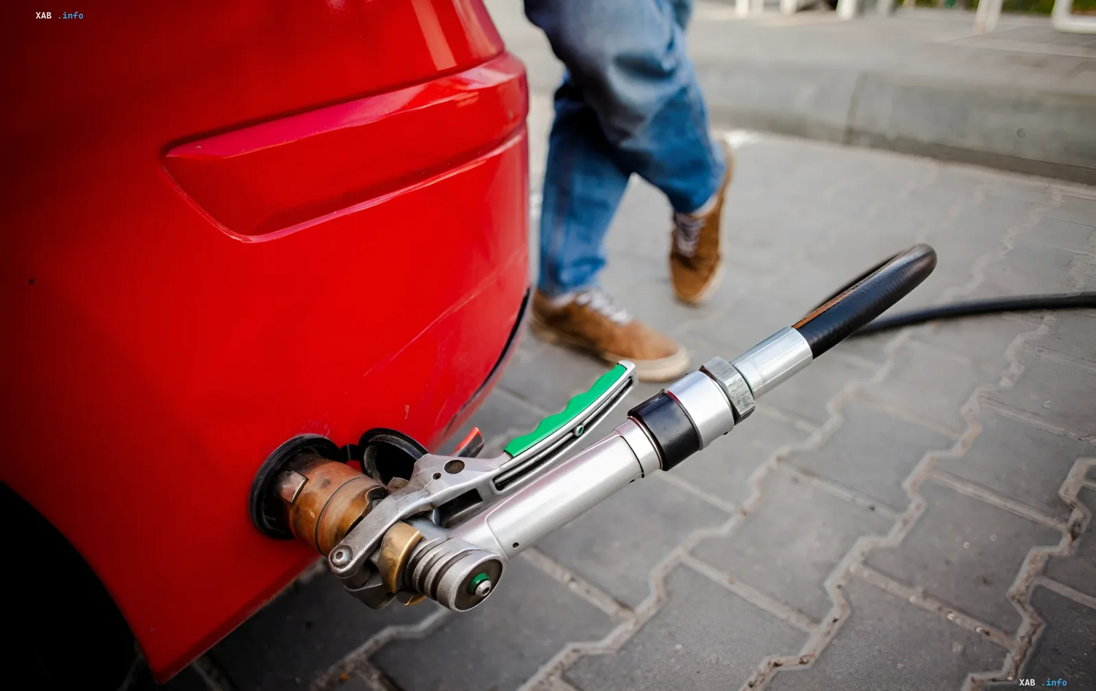 Gas refueling of a car: a nozzle inserted into the fuel tank of a red car, illustrating the topic of switching to gas fuel