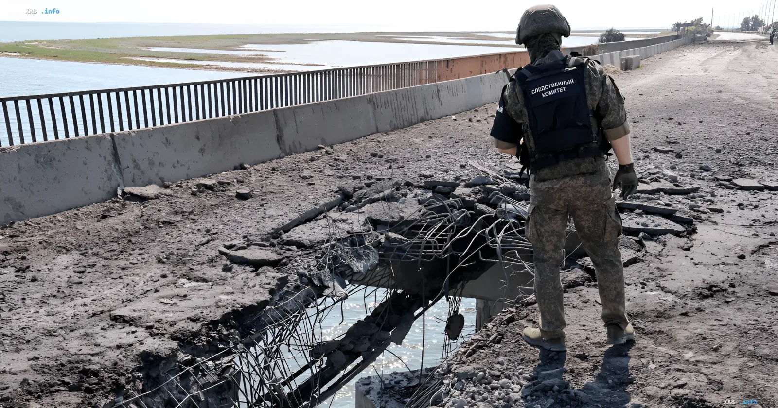 Zerstörter Abschnitt der Krim-Brücke mit freiliegendem Bewehrungsstahl und Beton, im Hintergrund steht ein Mitarbeiter des russischen Untersuchungsausschusses in Tarnuniform