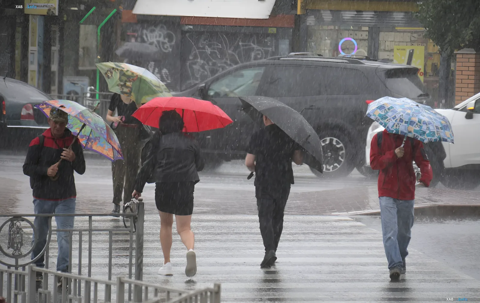 Люди з парасольками йдуть вулицею під час сильного дощу в Україні 11 червня
