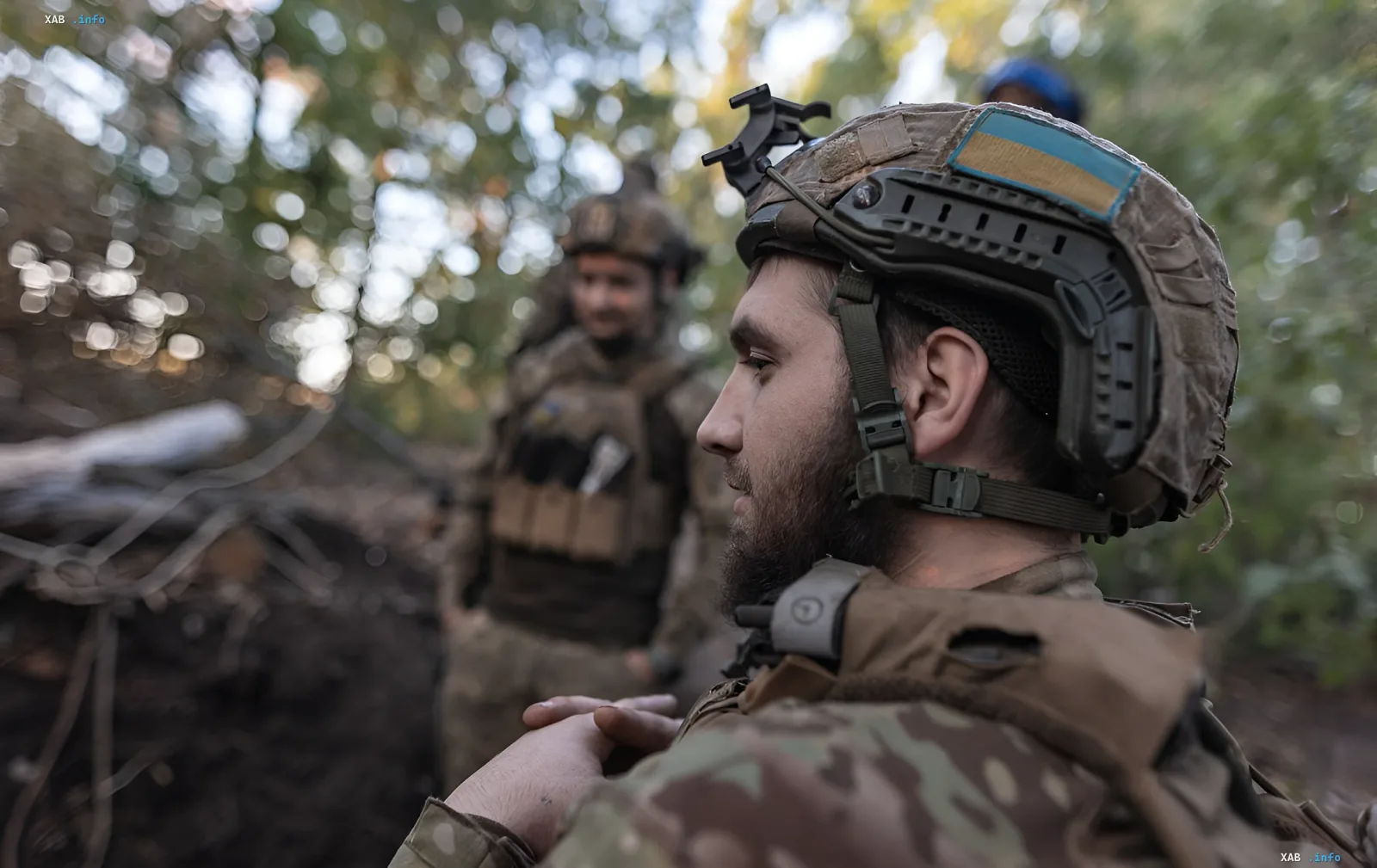 Ukrainian soldier in helmet with Ukrainian flag in forest, symbolizing demobilization expectations tied to conscription