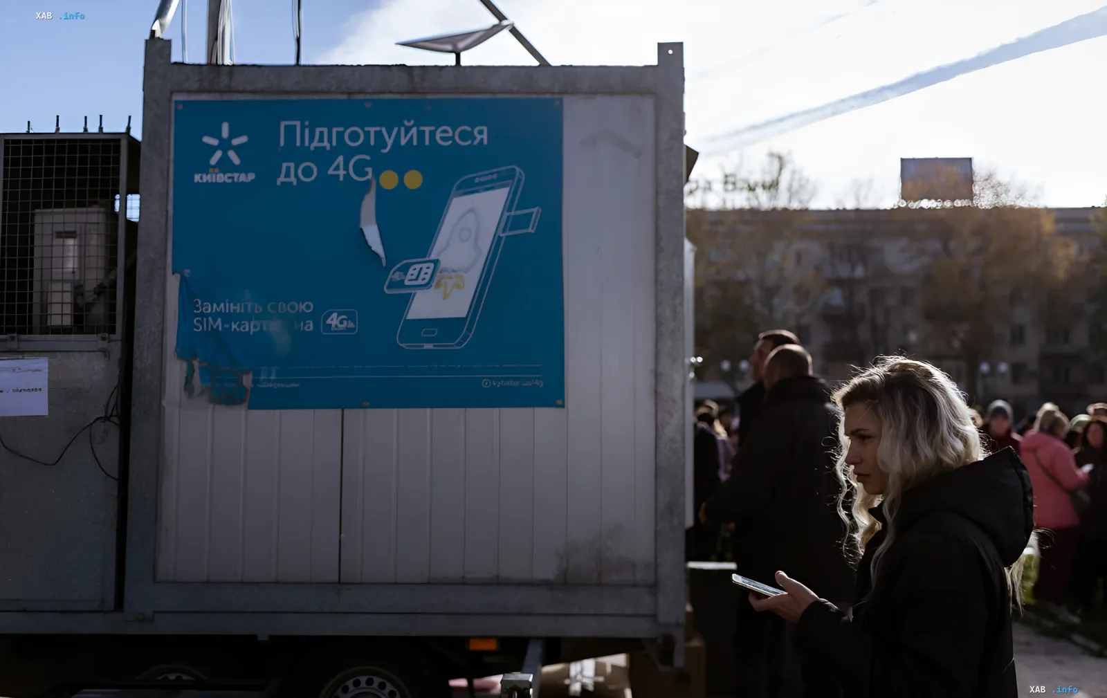 Рекламный щит Киевстар с призывом перейти на 4G, установленный на мобильной вышке; рядом стоит женщина с телефоном, символизируя переход от 3G к новым технологиям