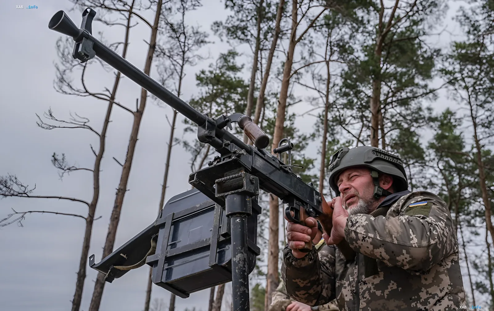 Украинский военнослужащий в камуфляже и шлеме управляет зенитным пулеметом в лесу, отражая массированную атаку российских дронов и ракет «Искандер-М»