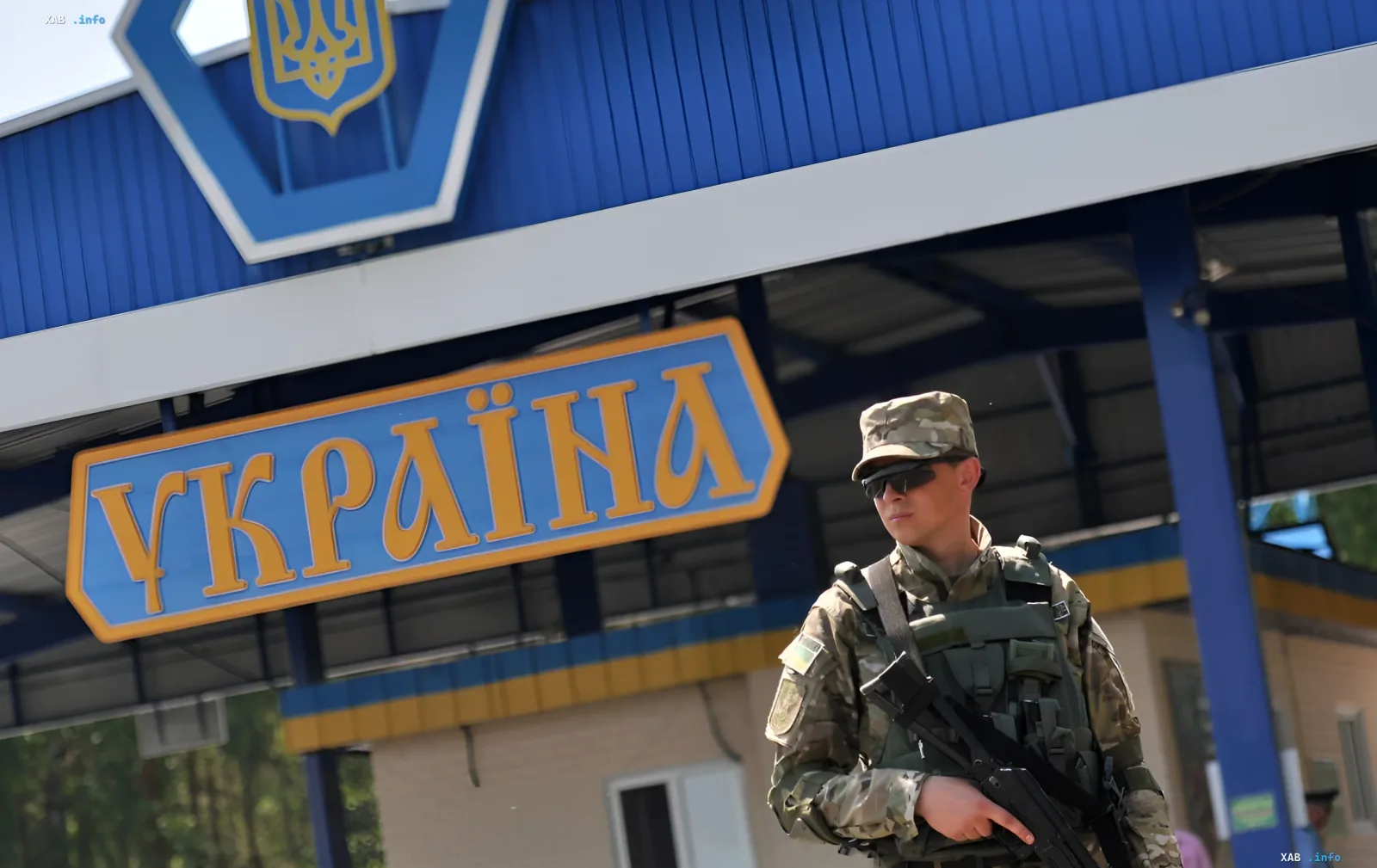 Украинский пограничник стоит у знака «Украина» на пункте пропуска Шегини, символизируя работу границы даже во время ремонта