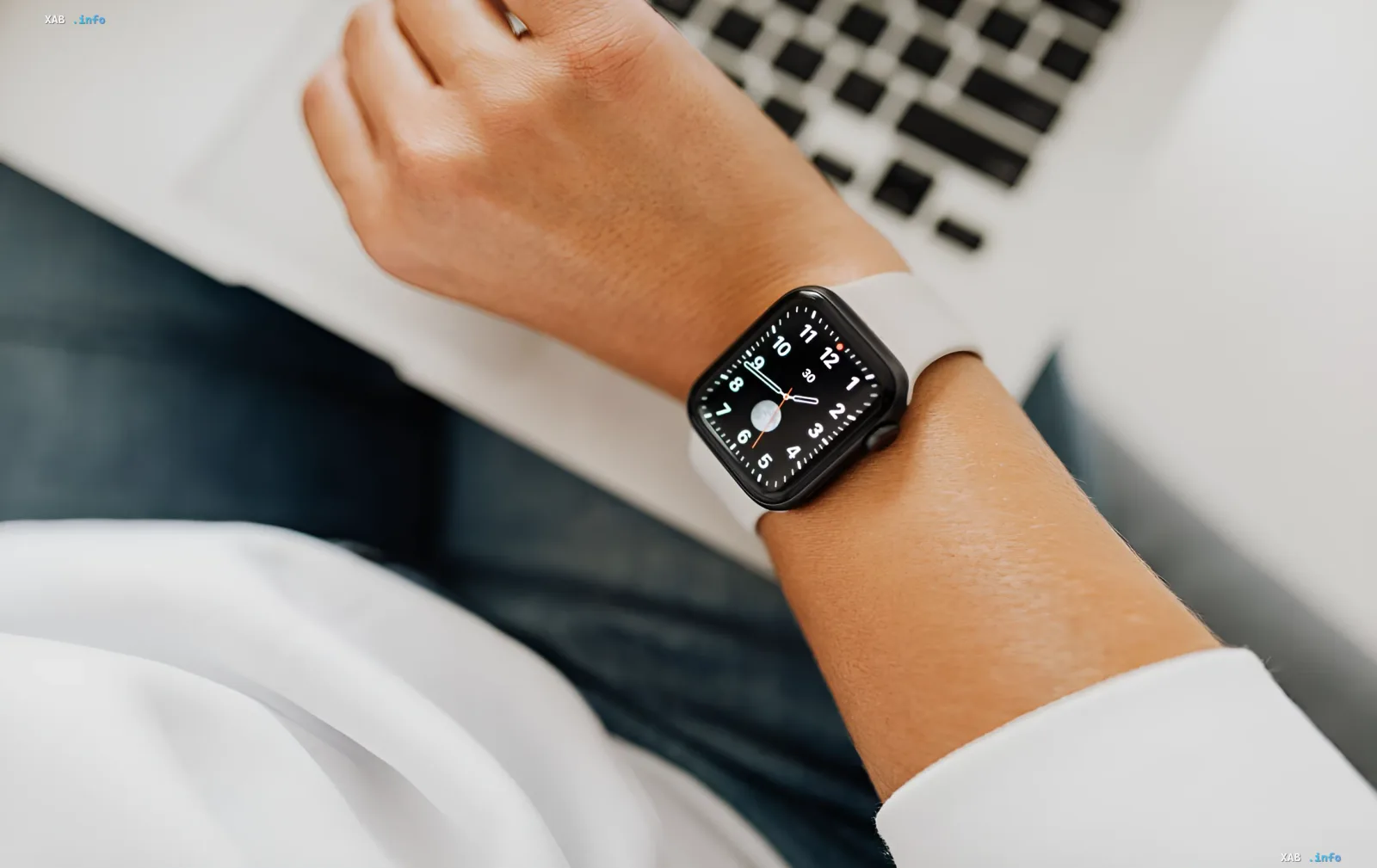 Person wearing Apple Watch while working on laptop — illustrating watchOS 27’s independence from iPhone