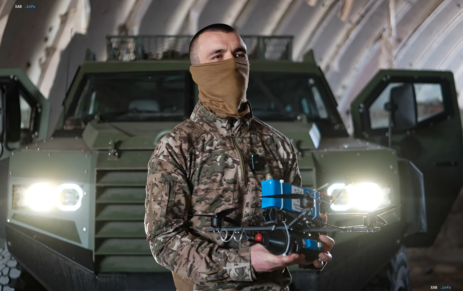 Украинский военный в камуфляже держит боевой дрон, на фоне бронетранспортер; иллюстрация к статье об эффективности Сил беспилотных систем