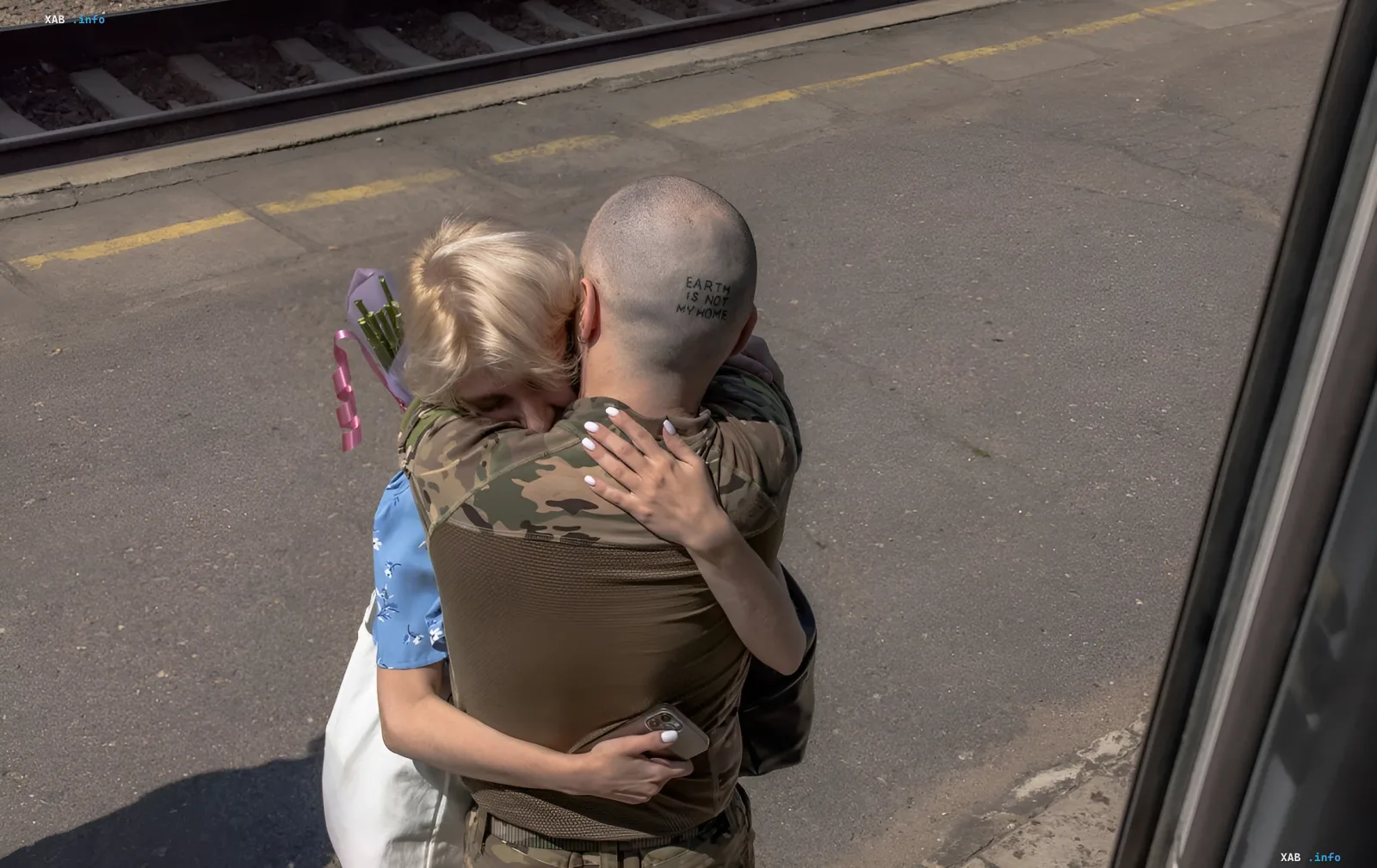 Военнослужащий в камуфляже обнимается с гражданской на железнодорожной платформе, символизируя прощание или возвращение в контексте военной реформы Украины