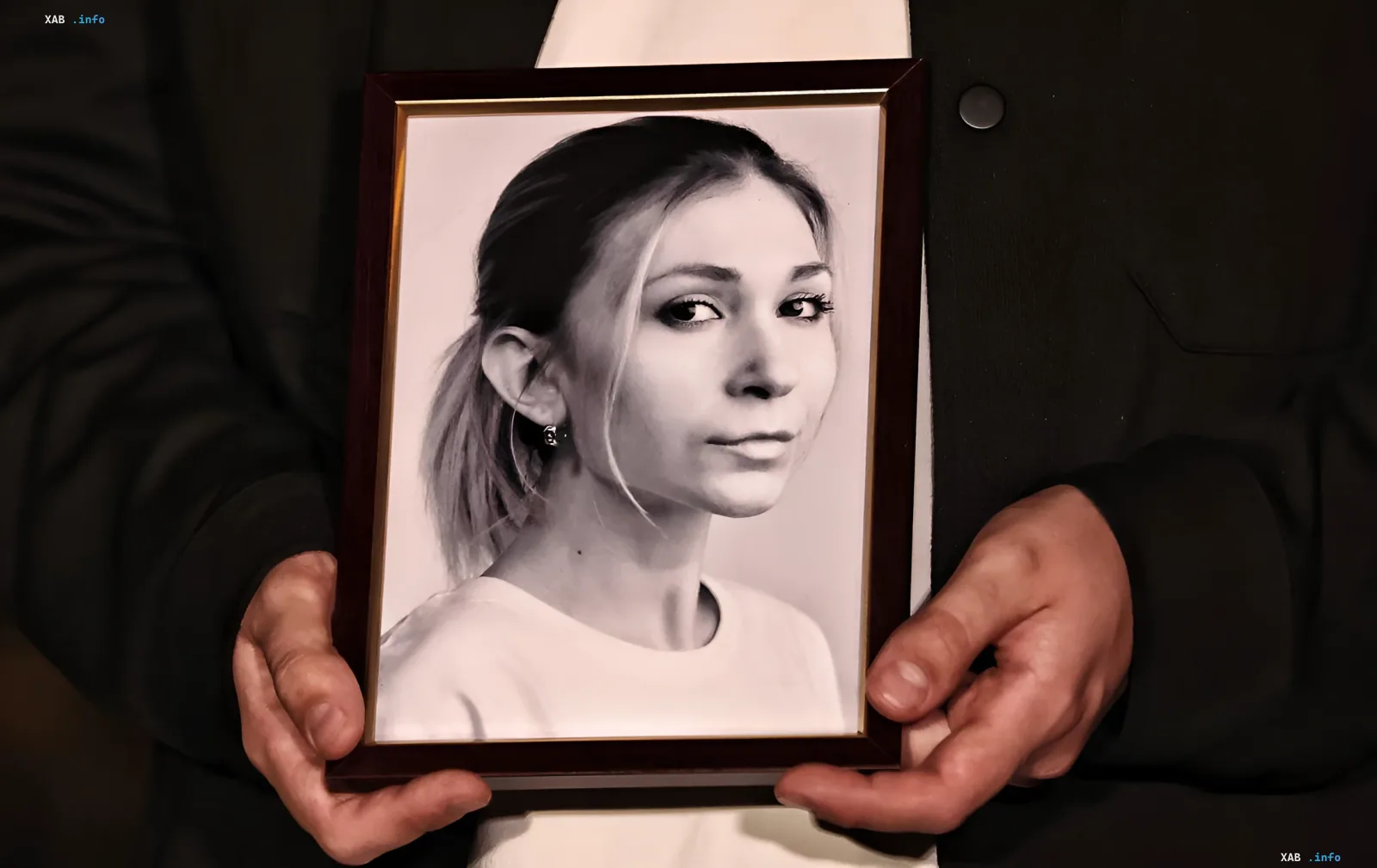 Hands holding a framed photo of Anna Roschina — symbol of the tragedy that prompted Ukraine to sanction judge Vakhrameev and pro-Kremlin media outlets