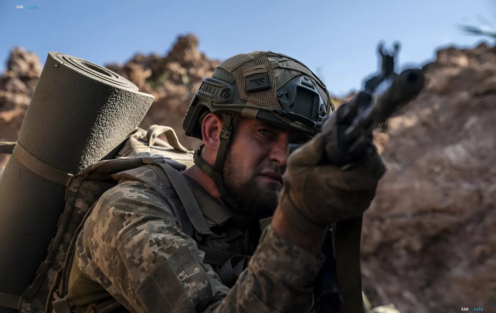 Украинский военнослужащий в камуфляже с рюкзаком и оружием на фоне гористой местности, иллюстрирующий тему нового контракта в армии