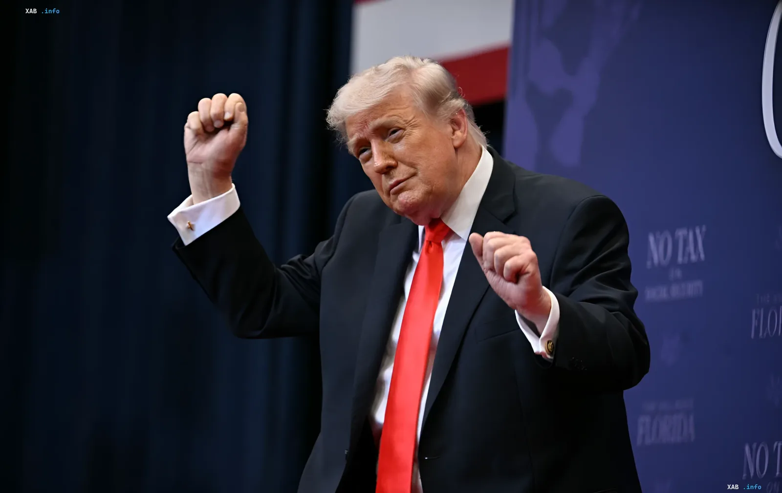 Дональд Трамп в красном галстуке на фоне синего баннера с надписью 'NO TAX', демонстрируя силу и энергию перед 80-летием