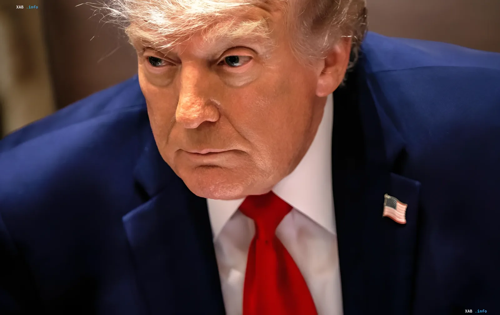 Дональд Трамп в синем костюме с красным галстуком и американским флагом на лацкане, выражение лица серьезное — в контексте его критики Израиля и попыток спасти сделку с Ираном