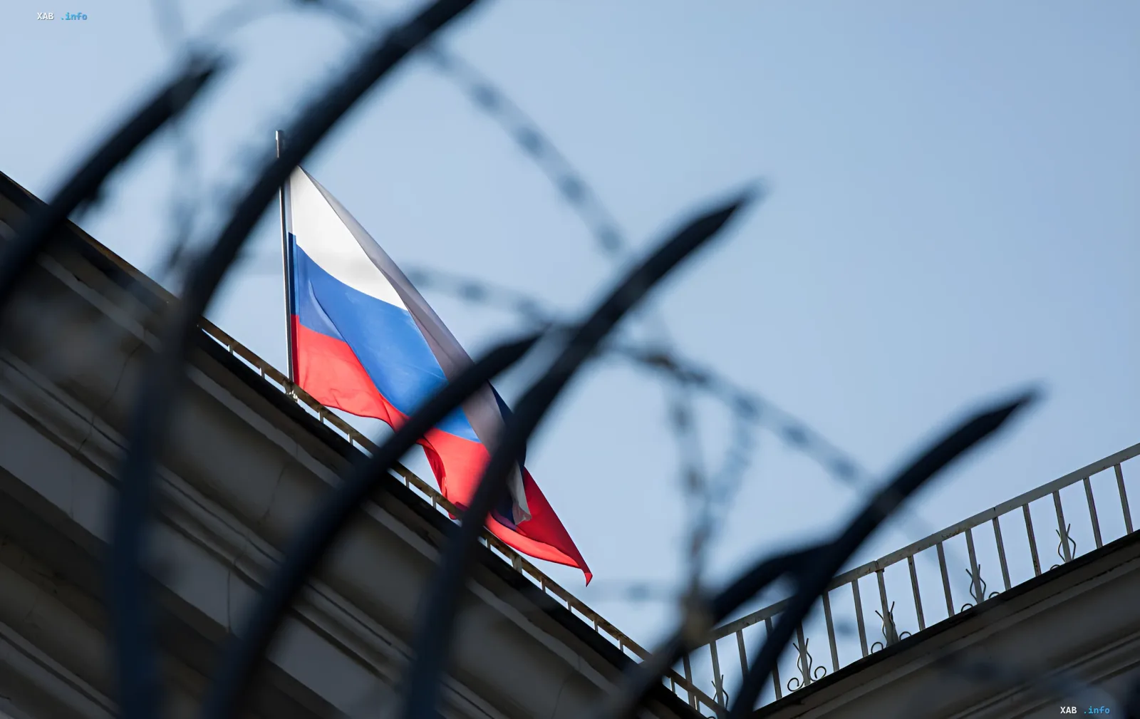 Russische Flagge vor Stacheldraht, die neue EU-Sanktionen gegen die russische Militärmaschine symbolisiert