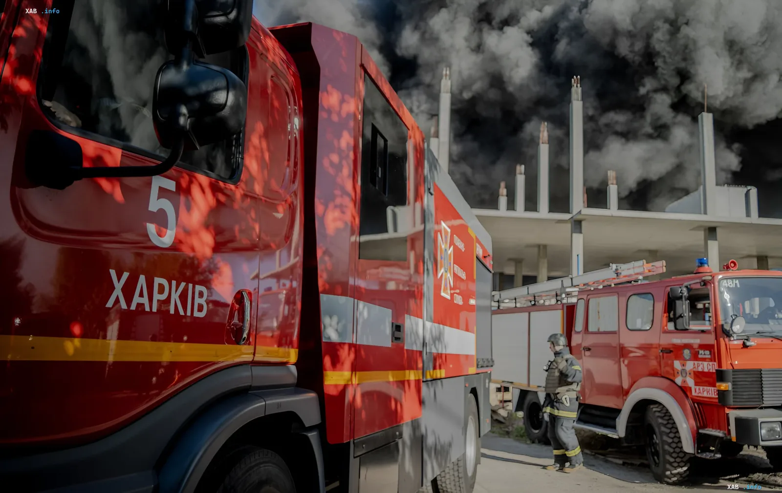Feuerwehrfahrzeuge in Charkiw vor einem Hintergrund aus Rauch nach einem zweiten Schlag am Ort der Beseitigung der Folgen eines Beschusses