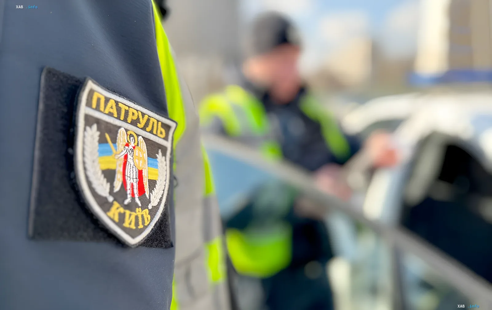 Патрульна поліція Києва у формі з нашивкою "Патруль Київ" на фоні поліцейського автомобіля, що бере участь у припиненні заворушень біля ТЦК