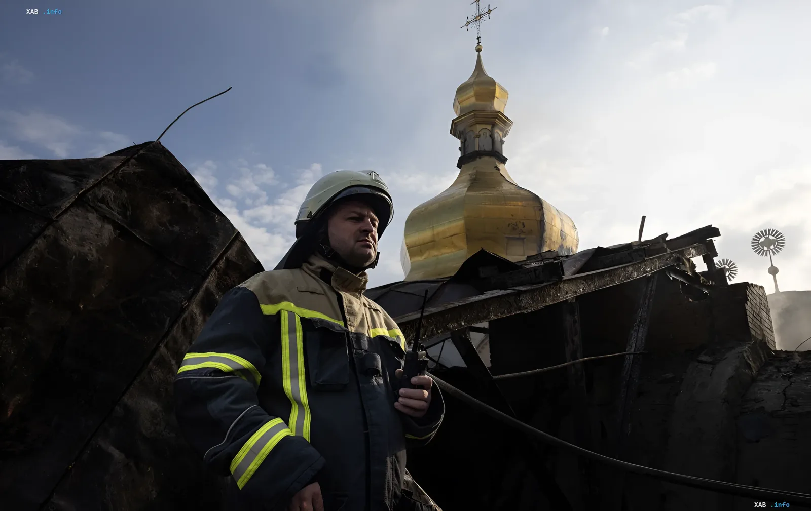 Пожарный стоит на обгоревшей крыше Успенского собора после атаки российских дронов, на фоне золотого купола