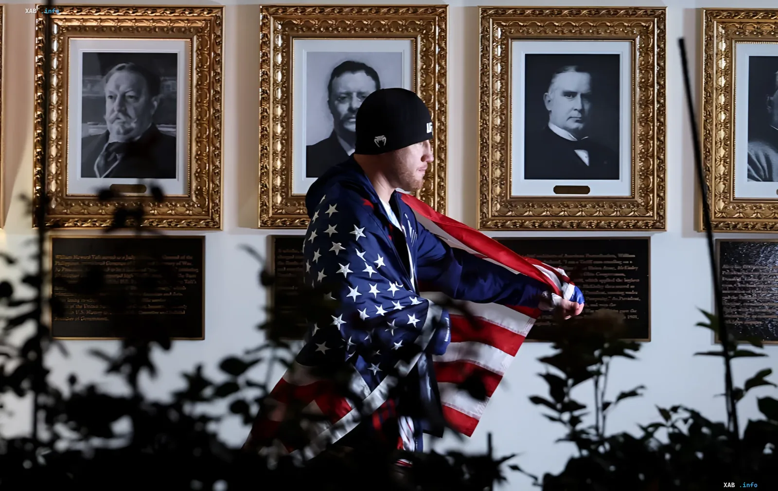 UFC fighter draped in American flag walks past portraits of U.S. presidents in White House hallway during Freedom 250 event