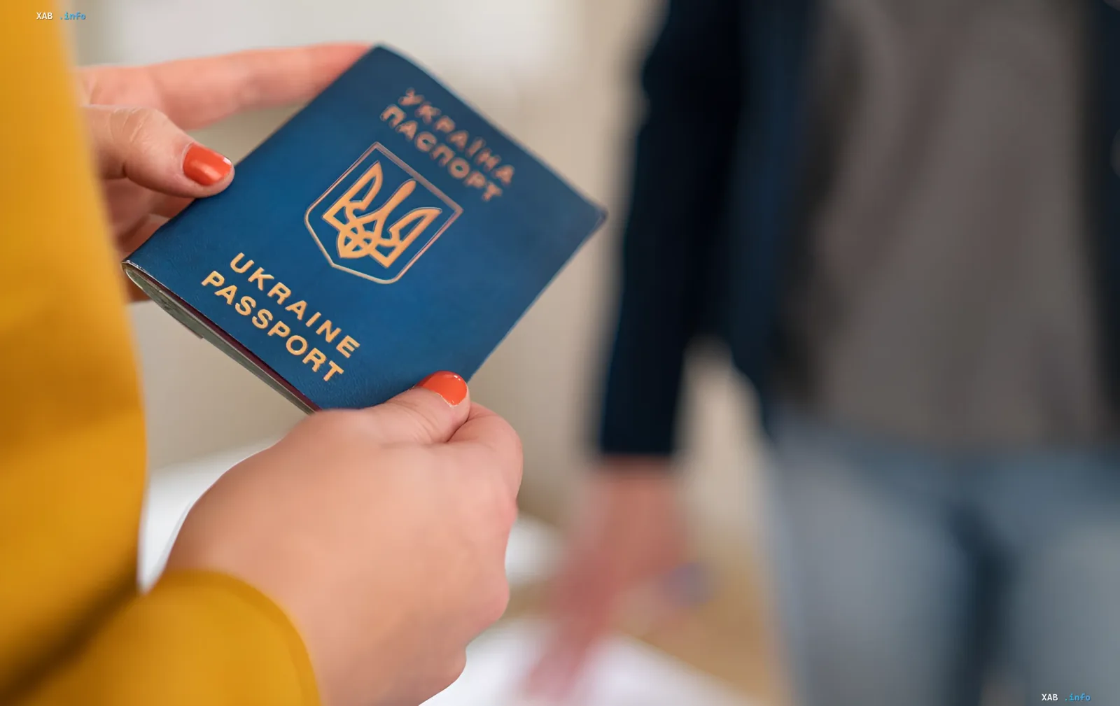 Женщина держит украинский загранпаспорт, символизирующий ограничения на выезд за границу