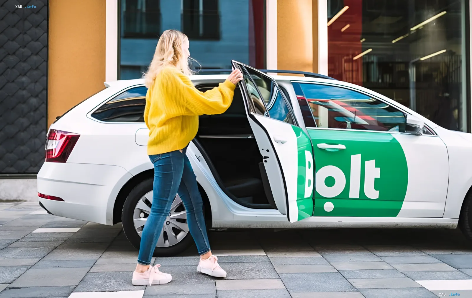Женщина в желтом свитере садится в белый автомобиль Bolt с открытой дверью, символизируя рост числа женщин-водителей в Bolt Украина