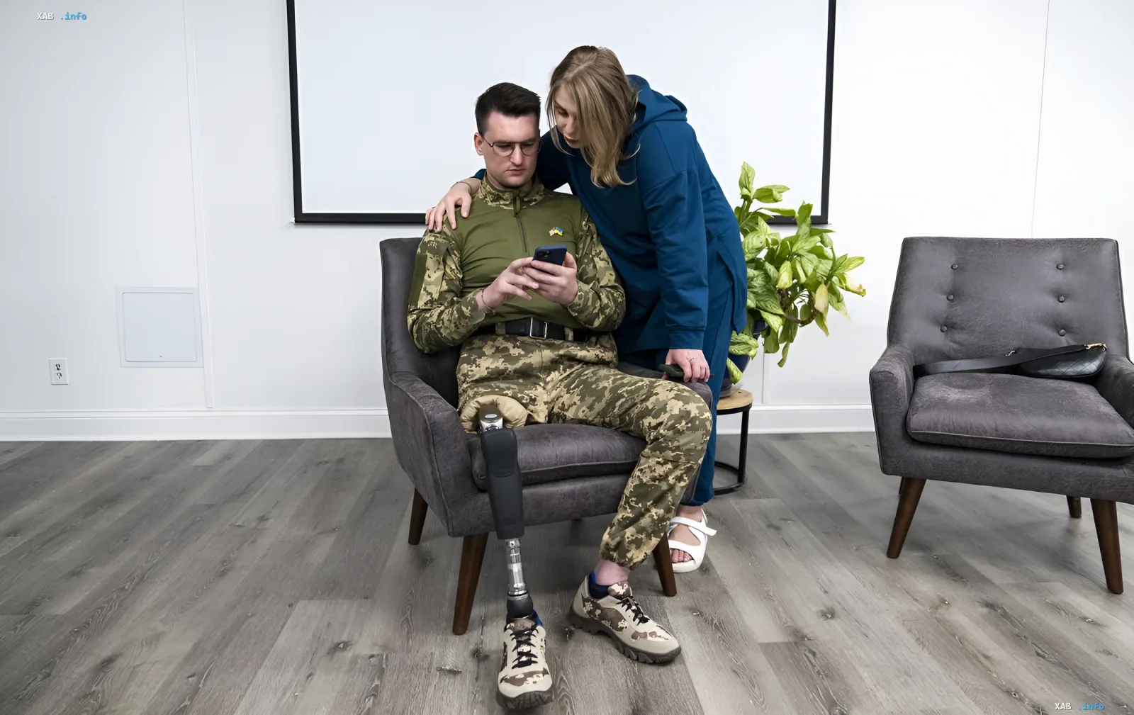 Veteran with a prosthetic leg in military uniform looks at a smartphone while a woman supports him, illustrating the simplification of service access through digital platforms.