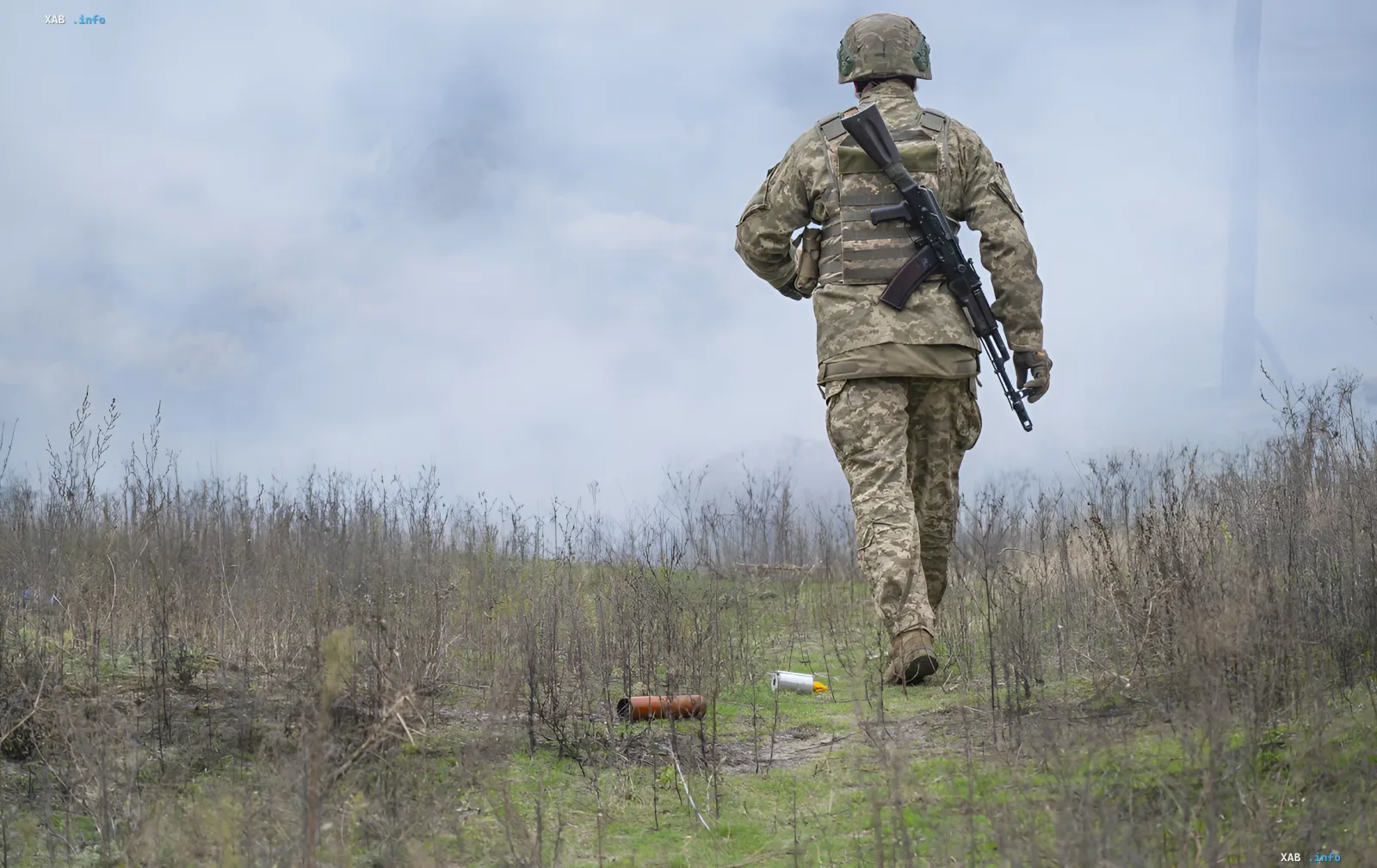 Военный в камуфляже с автоматом на фоне задымленного поля, иллюстрирующий тему фейков о Константиновке