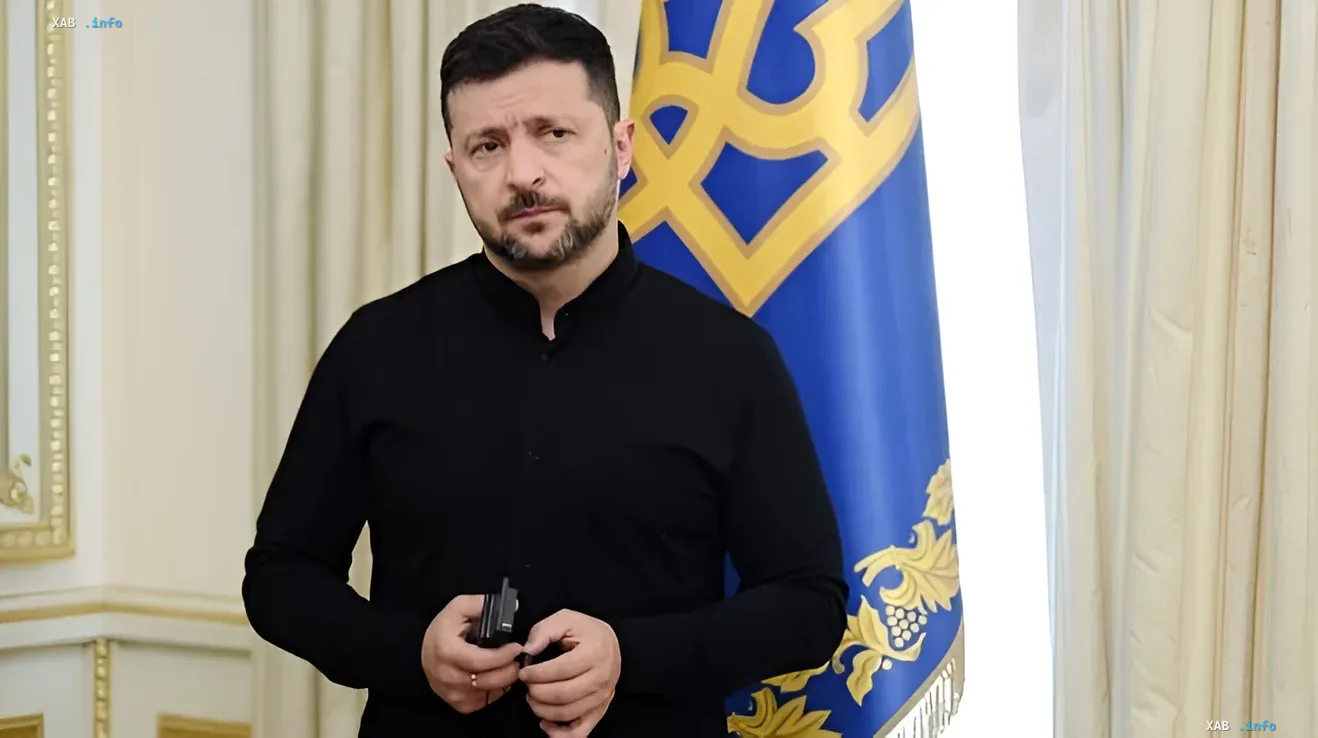 Ukrainian President Volodymyr Zelenskyy in black shirt stands before Ukrainian flag holding microphone — readiness for peace negotiations