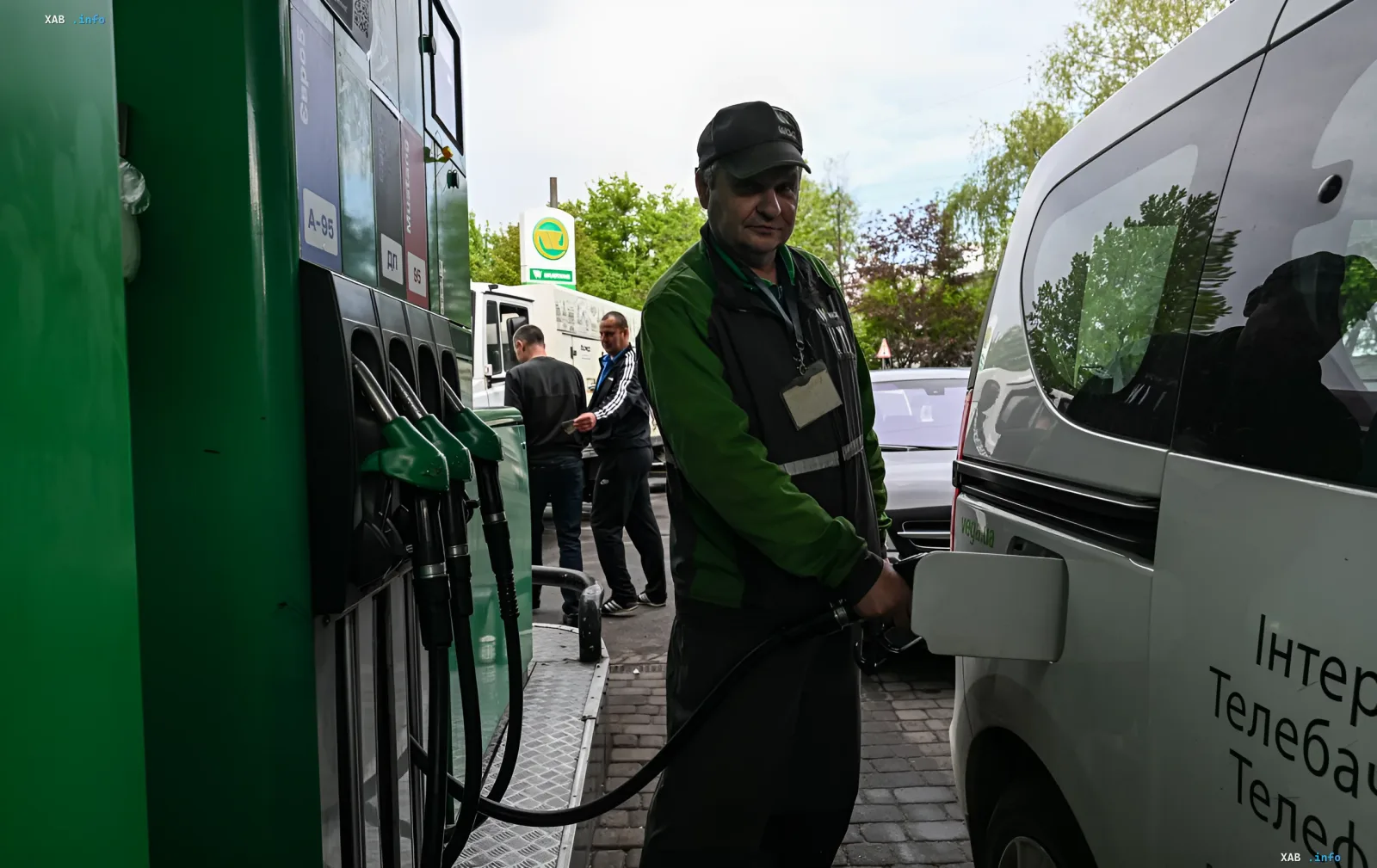 Заправщик заправляет белый фургон на АЗС на фоне падения цен на нефть и требований АМКУ снизить стоимость бензина