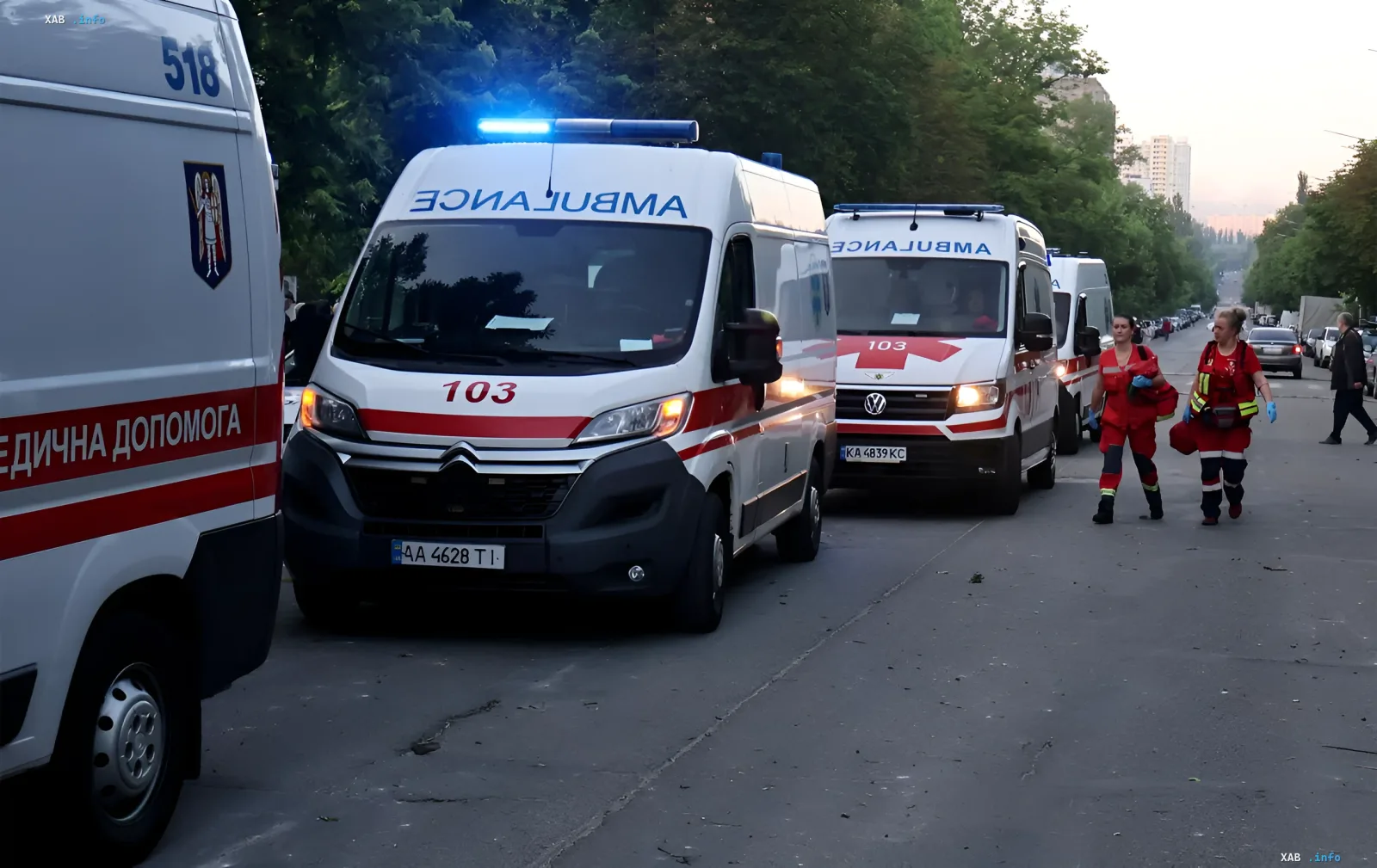 Колонна машин скорой помощи в Киеве во время тревоги. Медработники в красной форме бегут к месту вызова, иллюстрируя работу медицины под огнем.