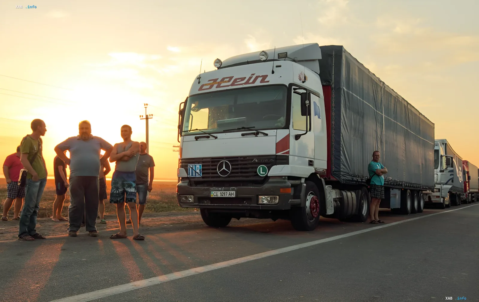 Водители большегрузов отдыхают на обочине дороги в Украине на фоне заката из-за жары и сезонных ограничений