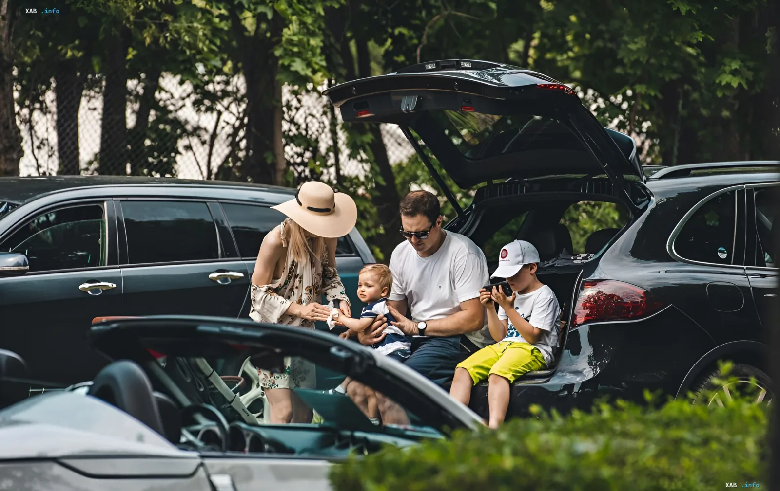 Familie lädt Gegenstände in den offenen Kofferraum eines SUVs, was die Praktikabilität der Karosserie für Familienreisen illustriert