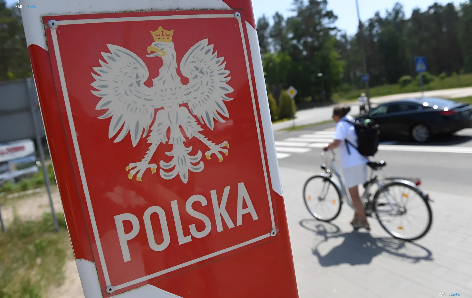 Граница Польши: знак с гербом орла и надписью POLSKA на фоне дороги с велосипедистом и автомобилем — символ контроля и цифровизации границ ЕС