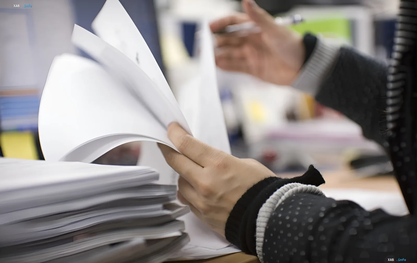 Hände bearbeiten einen Stapel Papierdokumente, was den Bedarf an einem Übergang von Papierbürokratie zu digitalen Diensten in der 'Diia'-App symbolisiert