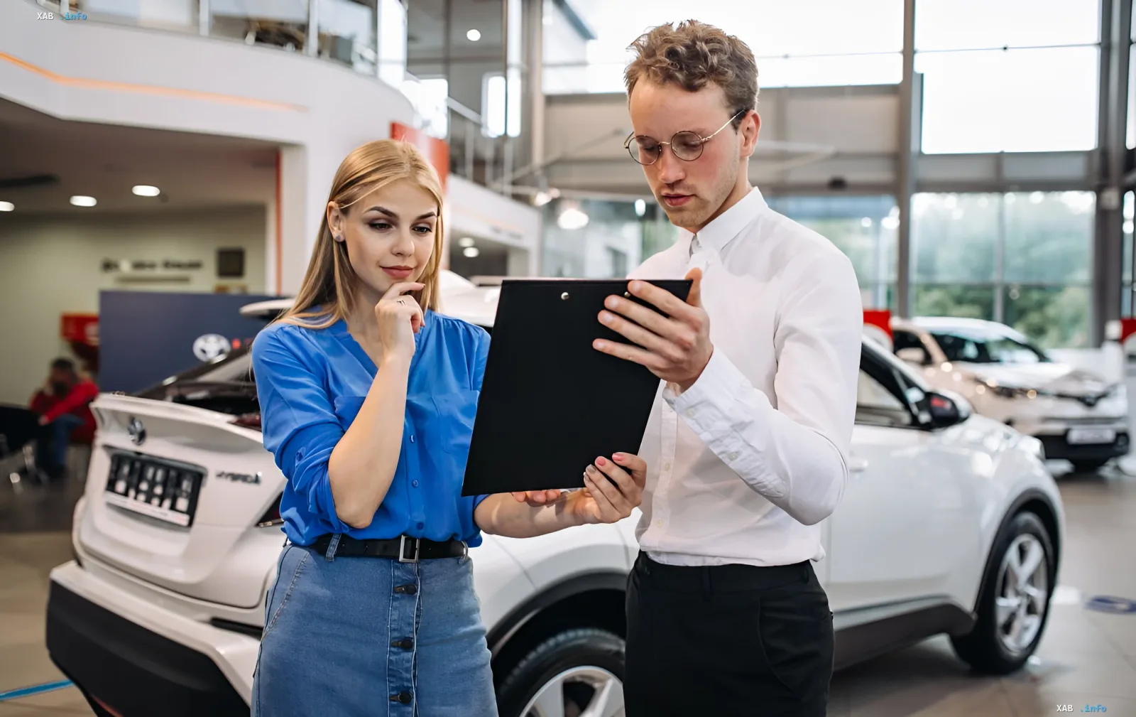 Young couple selecting a car in a showroom, discussing its value and liquidity as protection against inflation
