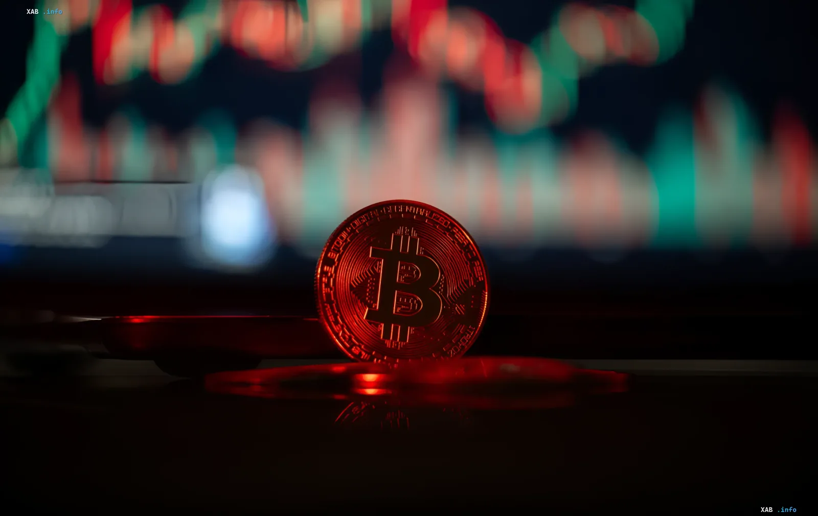 Золотая монета Bitcoin на переднем плане с красным свечением, на фоне размытого графика биржевых котировок — символ обвала курса ниже 60 тысяч долларов