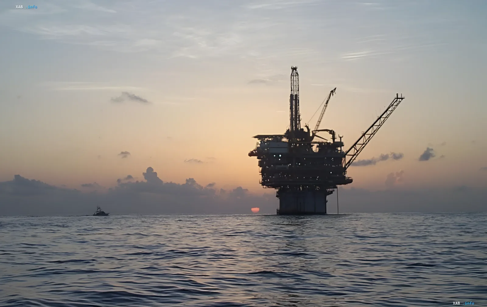Нефтяная платформа на фоне заката, символизирующая стабилизацию нефтяного рынка после открытия Ормузского пролива