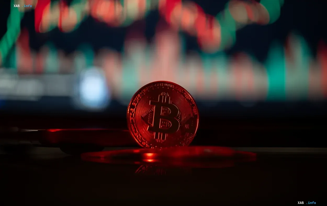 Физическая монета Биткоин на переднем плане с красным свечением, на фоне размытый график криптовалютного рынка с красными и зелеными свечами — символ падения цены BTC ниже $60 000 и оттока капитала в акции ИИ и облигации