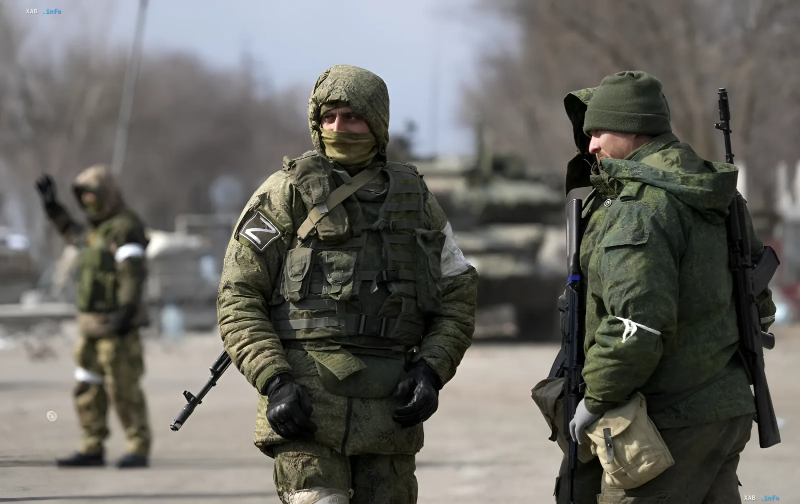 Russische Soldaten mit dem Buchstaben Z auf den Ärmeln stehen auf einer Straße in der Region Charkiw, im Hintergrund sind Panzerfahrzeuge sichtbar
