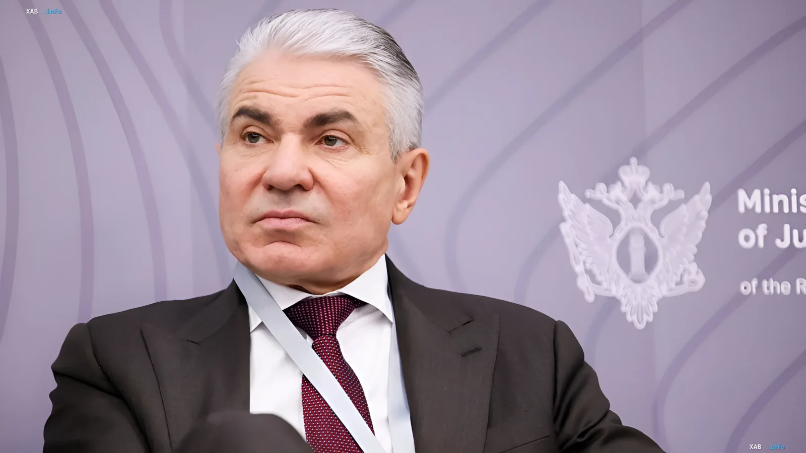 Russischer Justizminister Konstantin Chuychenko vor dem Logo des Justizministeriums, diskutiert KI-Inhaltsblockierungsanforderungen für ausländische Agenten
