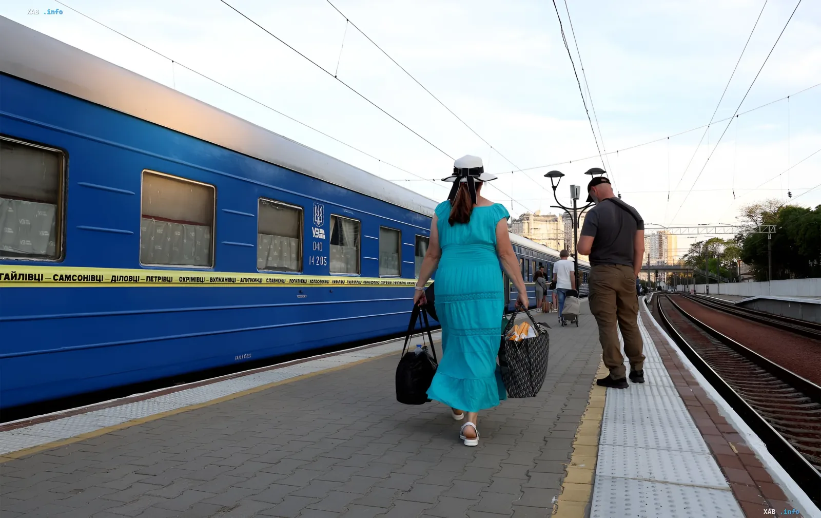 Passagiere mit Gepäck gehen am Bahnsteig zu einem blauen UZ-Zug — neue Schnellzugverbindung von Odessa an die Küste