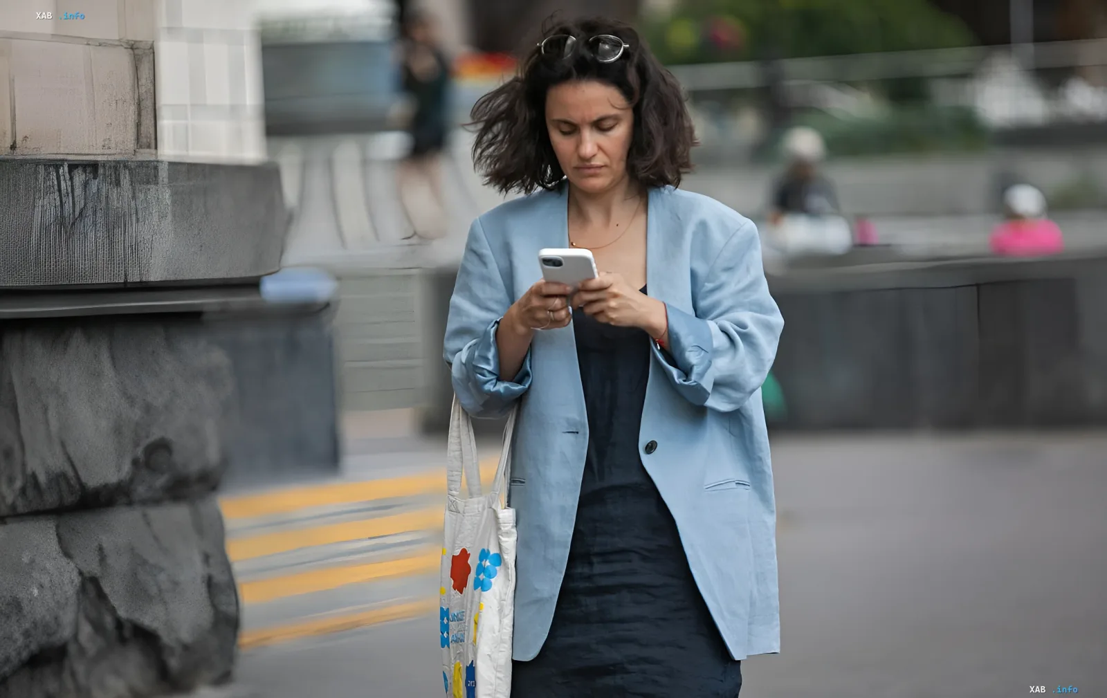 Frau im blauen Blazer schaut auf Smartphone, symbolisiert Abhängigkeit von mobilen Diensten, die in der Ukraine vorübergehend ausgesetzt werden