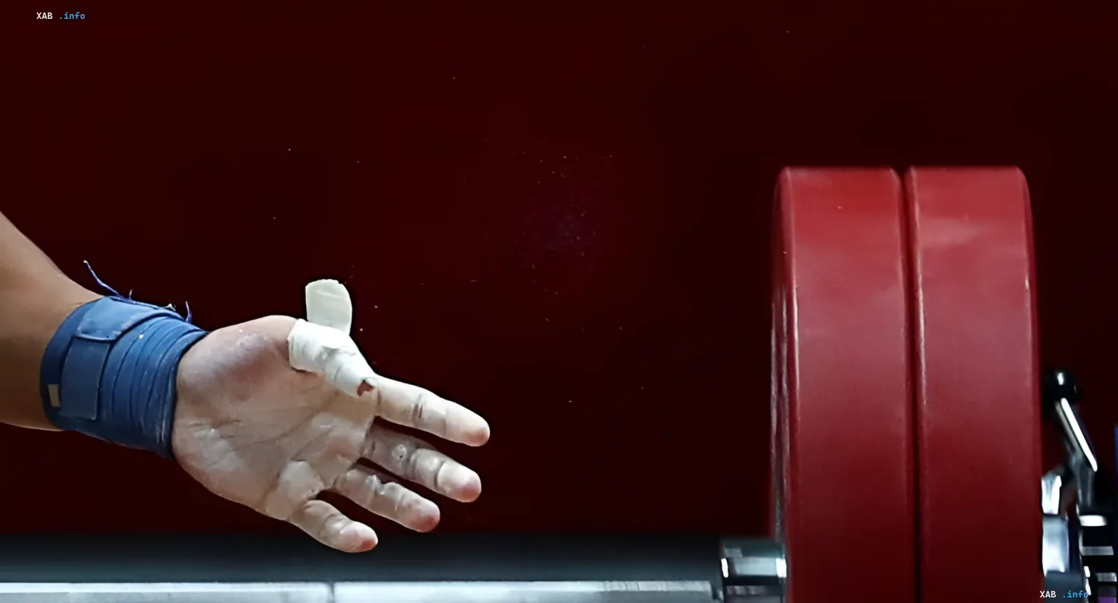 Weightlifter’s hand taped and chalked before red barbell plates — symbolizing the return of Russian and Belarusian athletes to international competition after IWF lifted all bans