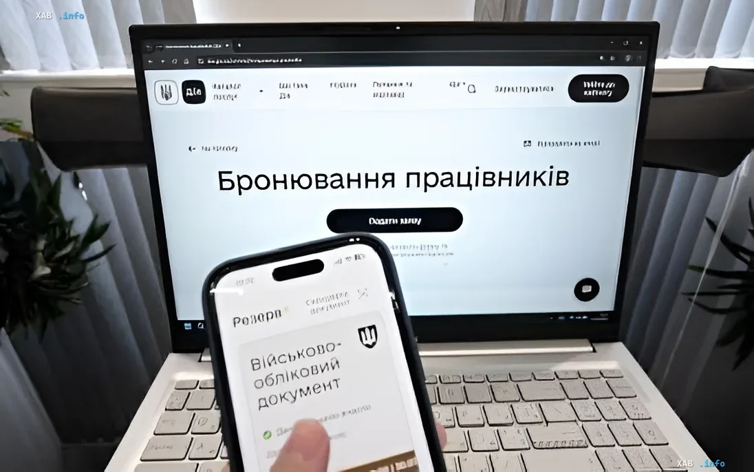 Smartphone mit 'Robota'-App und militärischem Ausweis vor einem Laptop mit Mitarbeiterbuchungsformular