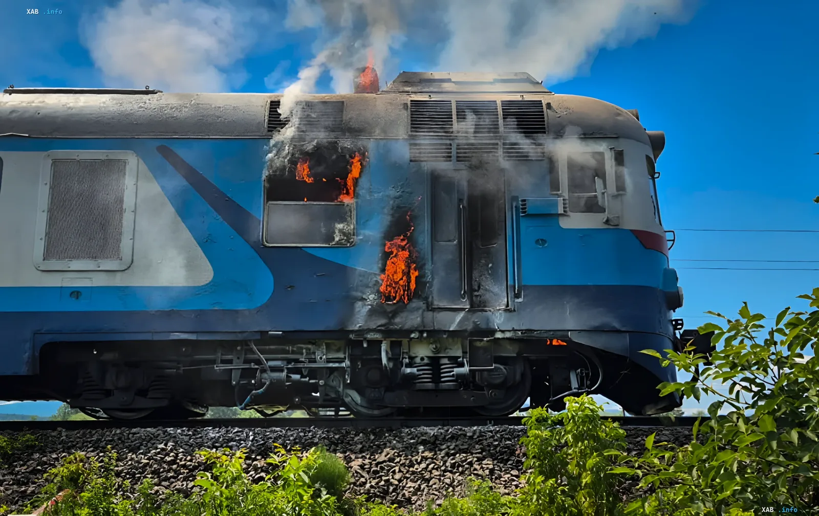 Suburban train on fire on railway tracks in Zakarpattia, flames and smoke coming out of windows and roof of the carriage