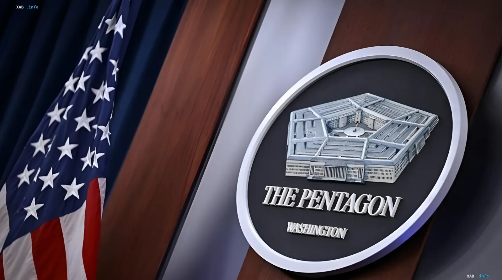 Logo des Pentagon vor dem Hintergrund der amerikanischen Flagge, das den Budgetstau und eingefrorene Mittel für die Ukraine symbolisiert