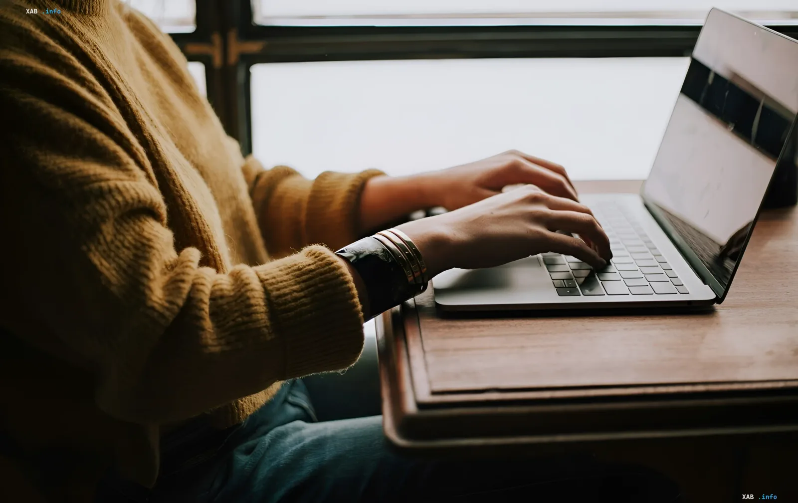 Человек печатает на MacBook, иллюстрируя тему сенсорного MacBook без чипов M6 и стратегии Apple в области искусственного интеллекта