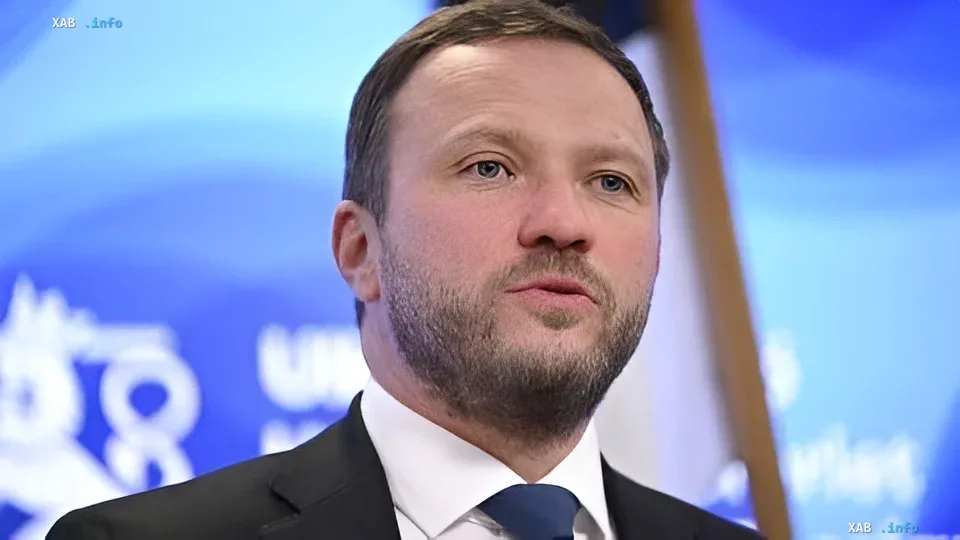 Глава МИД Эстонии в костюме на фоне синего баннера с логотипом, обсуждающий падение украинских БПЛА в НАТО как приемлемую плату за удары по России