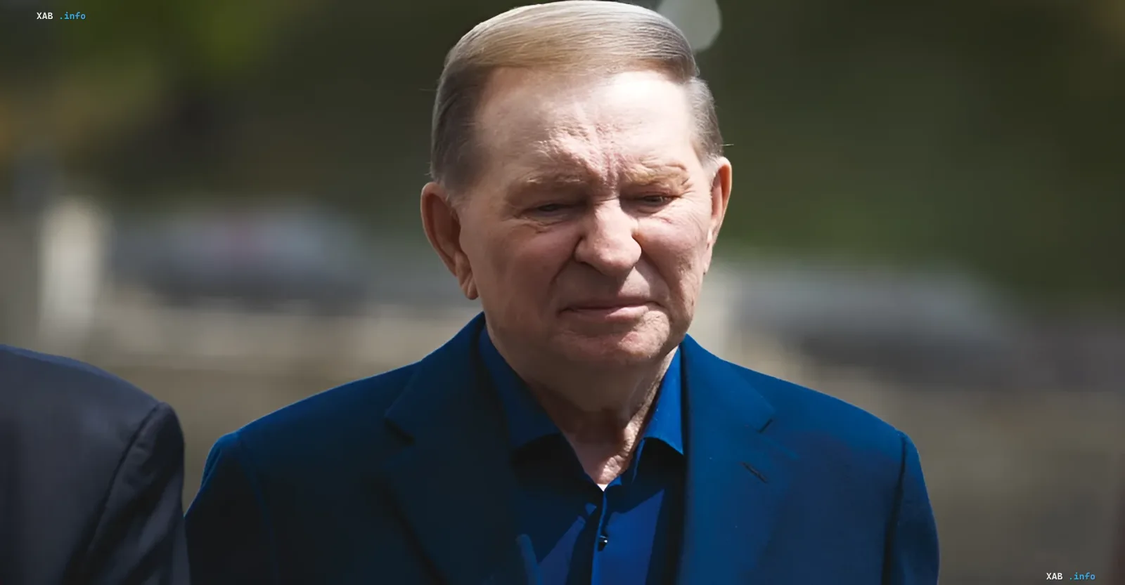 Leonid Kutschma in einem blauen Anzug vor einer verschwommenen Landschaft, diskutiert verfassungsrechtliche Barrieren für die Änderung der Grenzen der Ukraine
