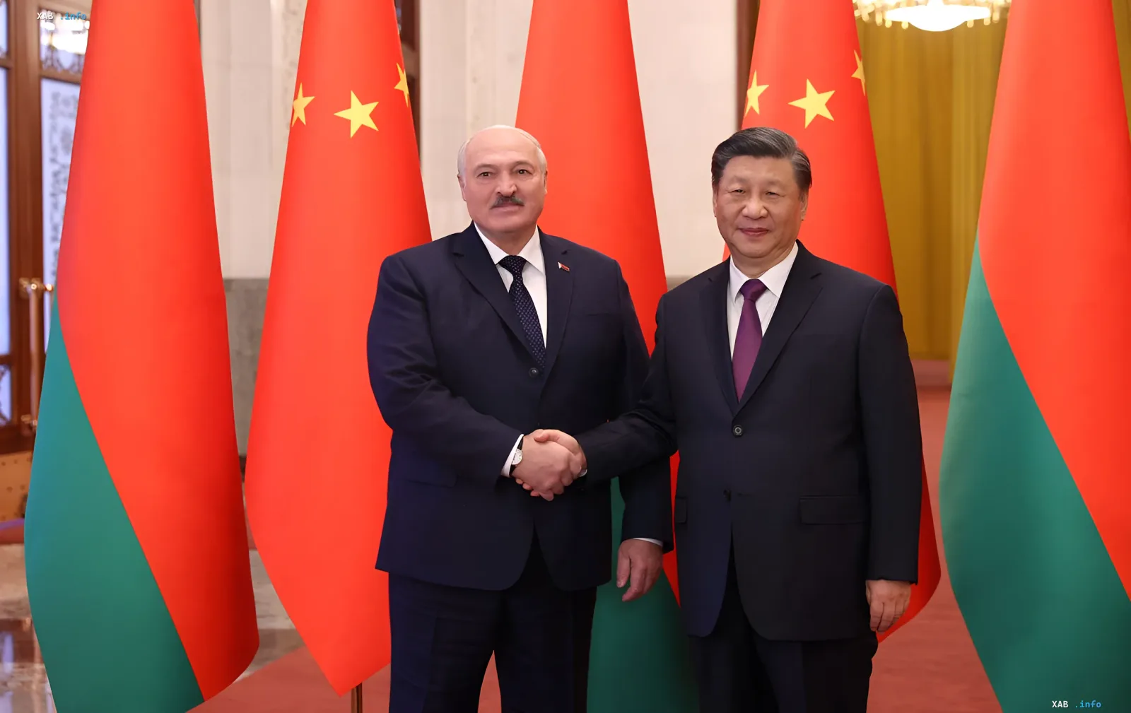 Александр Лукашенко и Си Цзиньпин пожимают руки на фоне флагов Беларуси и Китая во время встречи в Пекине