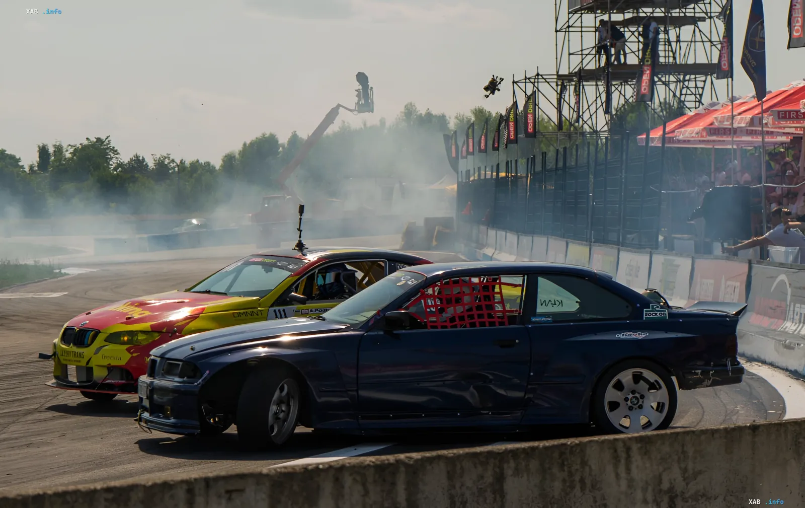 Дрифт-перегони на етапі Open Drift UA: синій BMW та червоно-жовтий автомобіль у димному змаганні, глядачі та трибуни на фоні