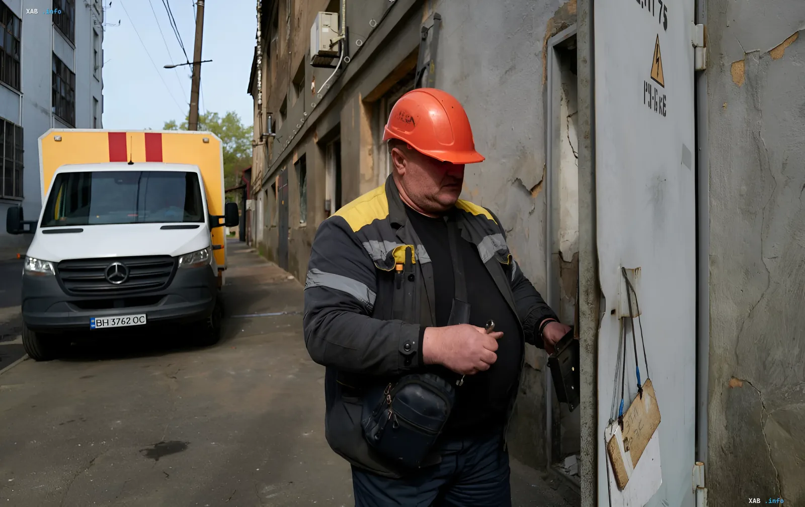 Electrician in an orange helmet performs emergency repairs on street equipment in Odesa or Sumy due to heat and power outages